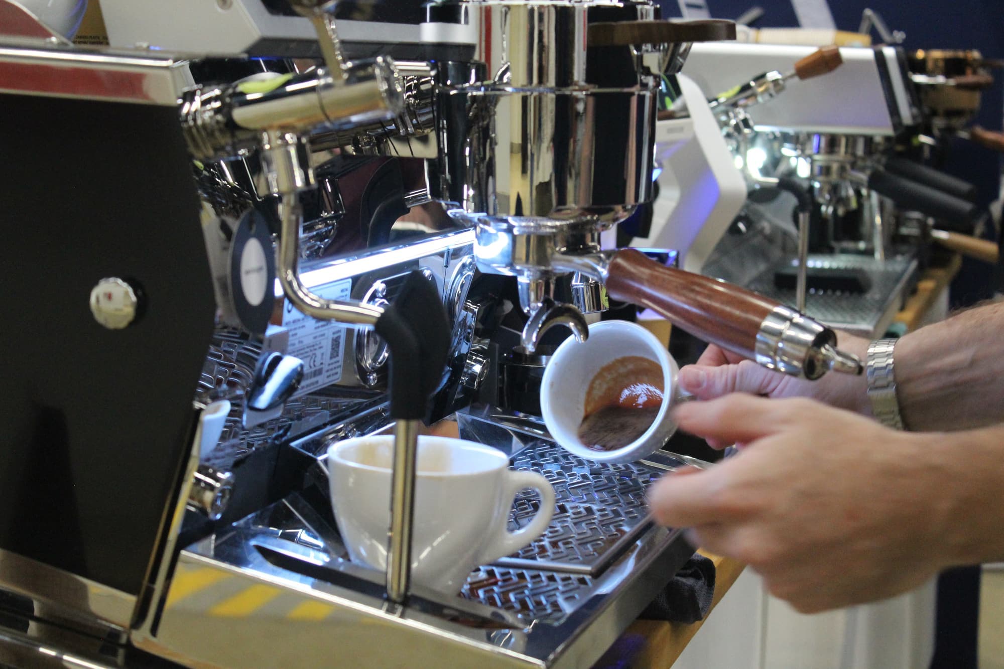 Mains d’un barista vérifiant l’extraction d’un espresso au bec de la machine