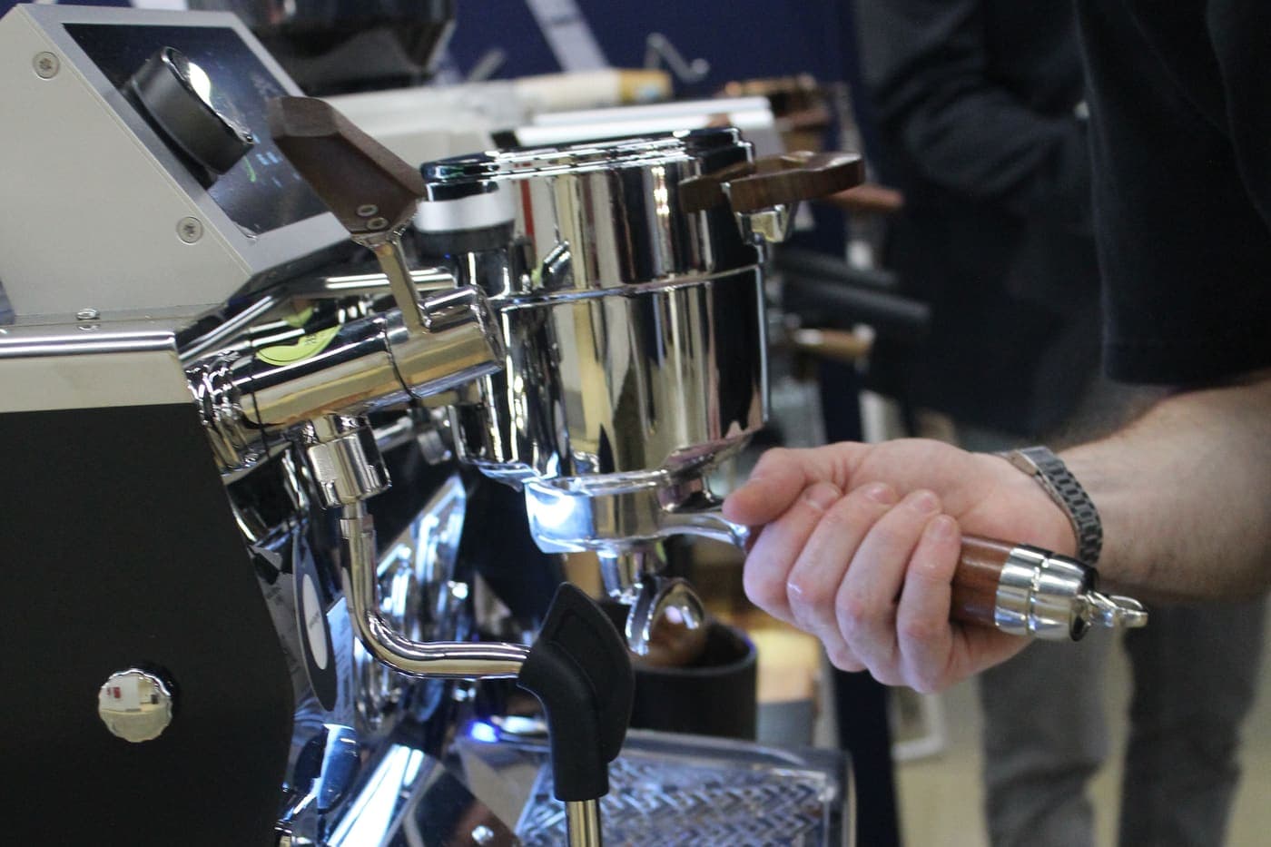 Barista verrouillant un porte-filtre à manche bois sur un groupe de machine espresso